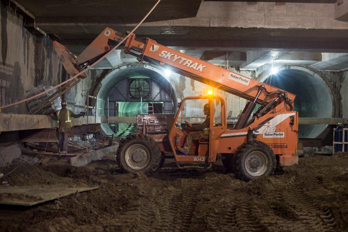 Orange Skytrak telehandler lifting materials inside underground transit station during construction.