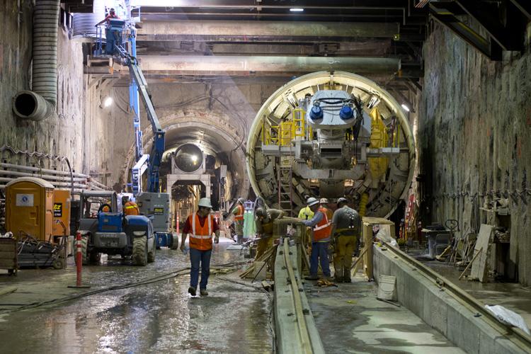 Tunnel boring machine Big Alma positioned in underground tunnel with construction workers and equipment preparing for tunneling operations.