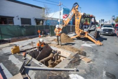 Construction crew excavating sewer line at 4th Street and Townsend Street intersection with heavy equipment.