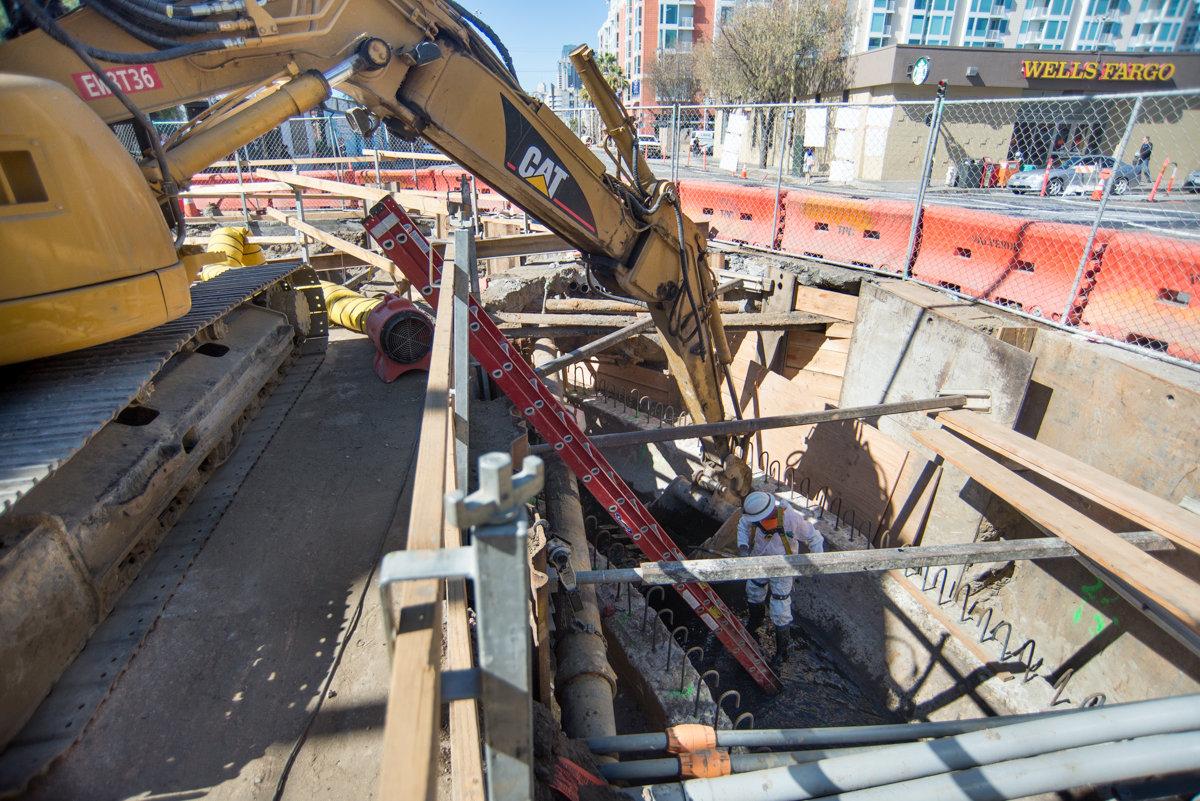 Construction site at 4th and Brannan showing excavation of century-old sewer line with heavy equipment and workers.