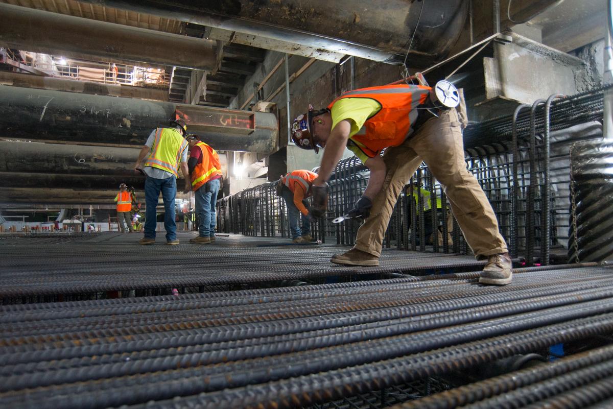 Construction workers install rebar on platform level invert slab for transit project.