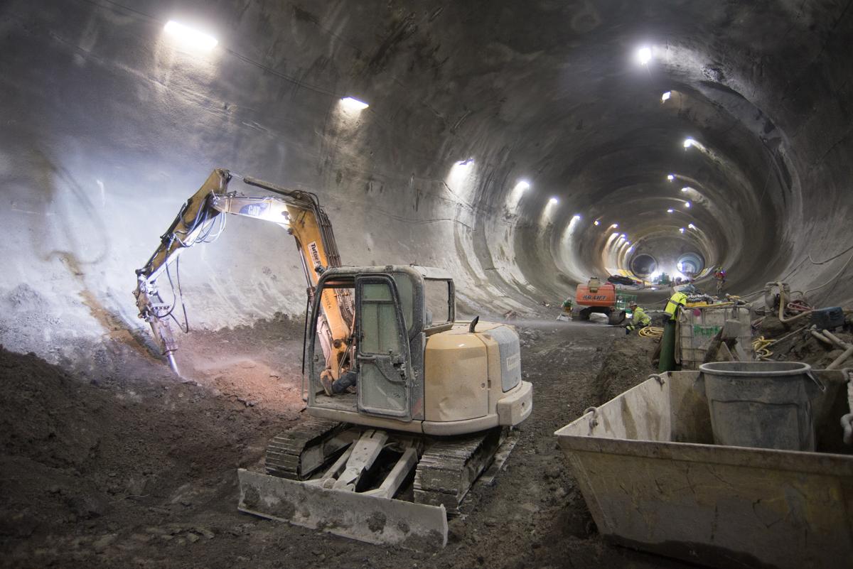 Excavation equipment and workers inside a large underground tunnel during transit construction.