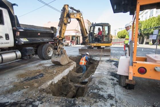 Construction crew excavating underground utilities on 4th Street for transit project work.