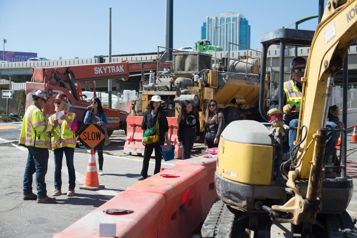 Construction crew conducts sidewalk and roadway restoration work at 4th and Bryant with heavy equipment and traffic control.