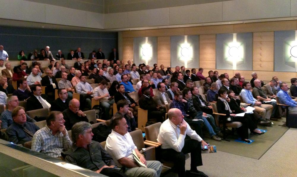 Large audience seated in an auditorium attending a pre-bid conference for transit construction contract.