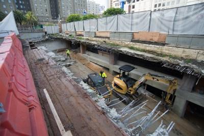 Construction equipment and workers inside Union Square Garage during roof deck installation and structural repairs.