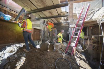 Workers in safety vests install steel beams for roof deck construction on O'Farrell Street.