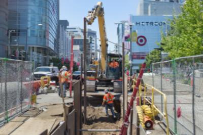 Construction crew operating excavation equipment and installing support structures at underground transit station site.
