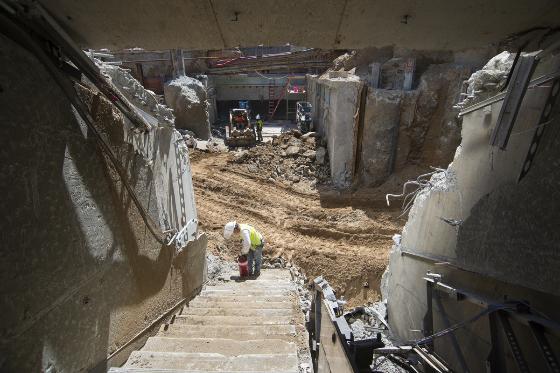 Underground stairwell under construction at Powell Station with exposed concrete walls and construction equipment below.