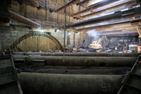 Underground tunnel construction with temporary steel bracing and support structures inside Chinatown Station headhouse.