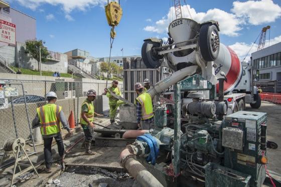 Construction workers pour cement from a mixer truck for station walls on 4th Street.