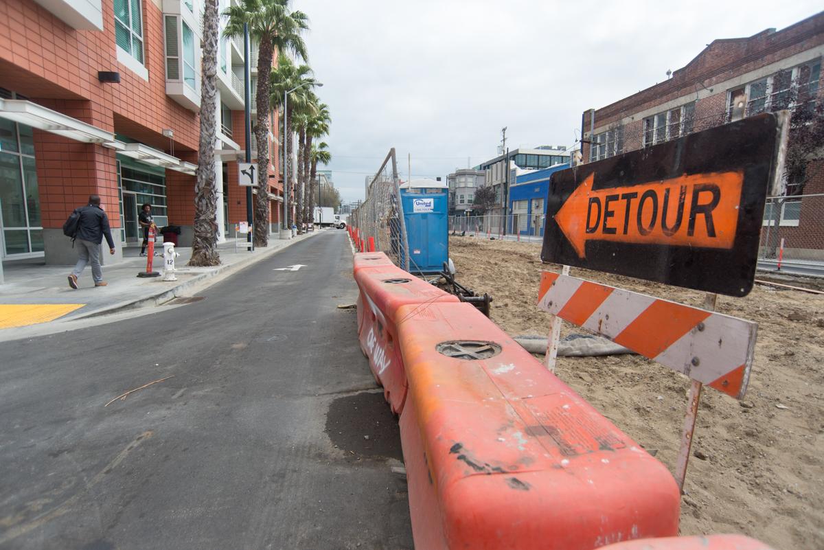 Street construction on 4th Street with detour sign, orange barriers, and relocated traffic lanes.