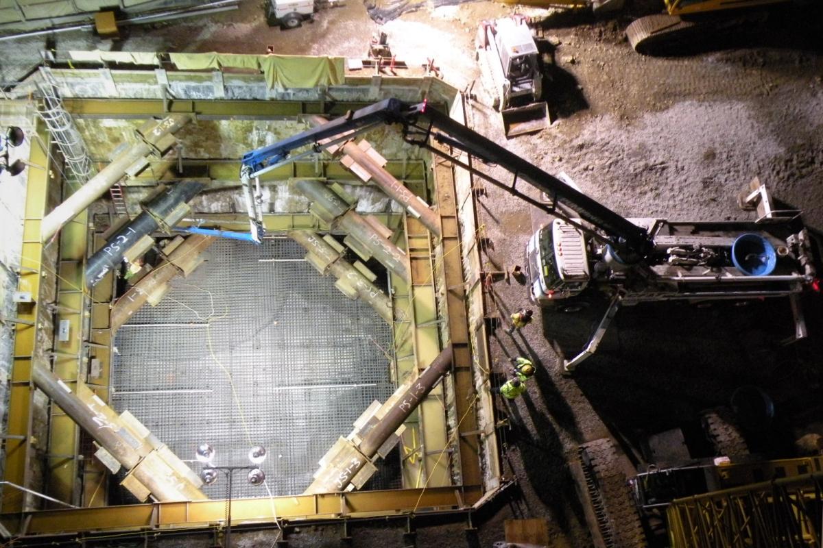 Overhead view of TBM retrieval shaft with concrete floor slab, support beams, and construction equipment on surrounding ground.