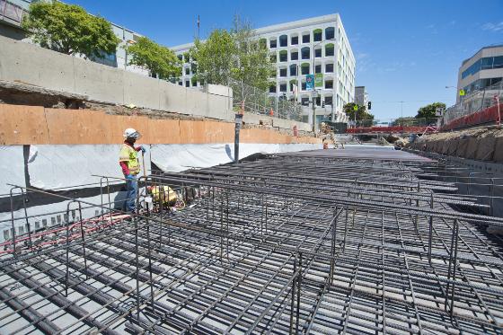 Construction worker inspecting steel rebar framework at Central Subway station site in San Francisco.