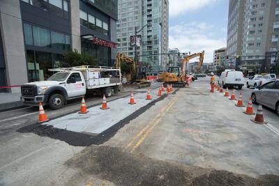 Construction site on 4th Street with utility work, traffic cones, and service vehicles.