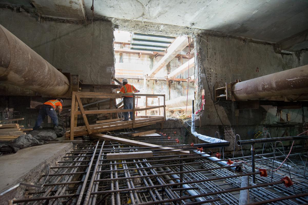Construction workers install reinforcement steel and concrete forms inside underground transit station headhouse.