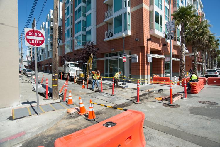 Construction site at 4th and Welsh with workers, equipment, and utility markings on street