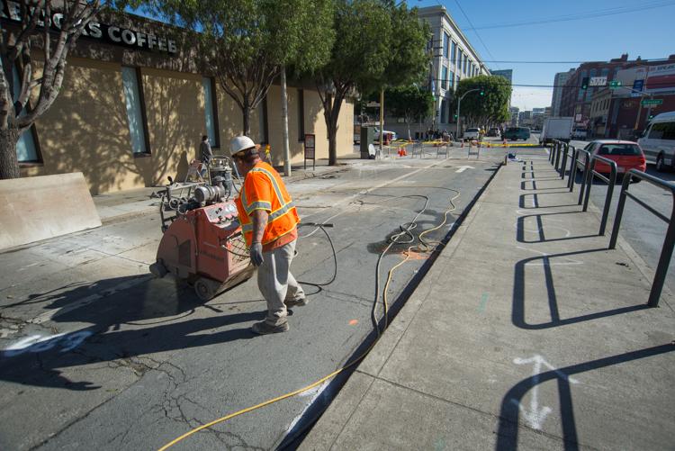 Worker operating concrete saw on 4th Street at Brannan during Central Subway construction.