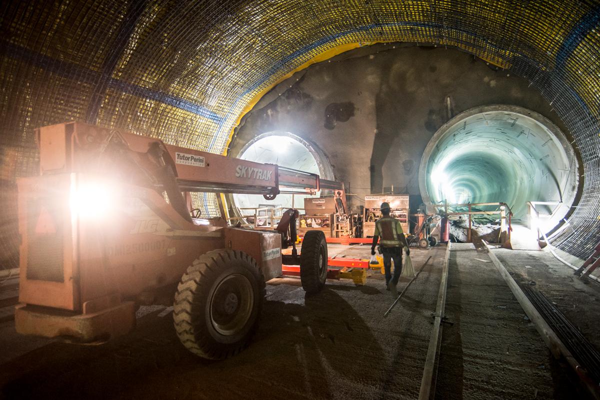 Workers and equipment inside illuminated tunnel during Central Subway construction in San Francisco.