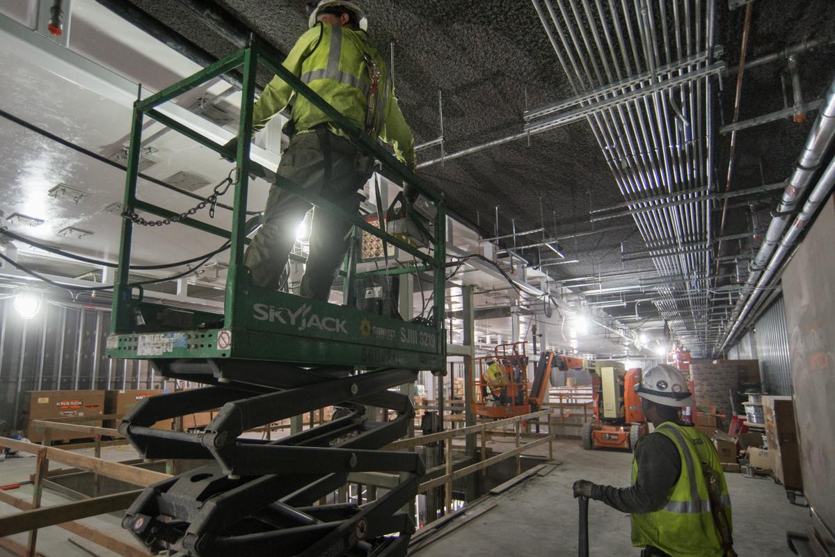 Worker on scissor lift installing plumbing lines inside Yerba Buena/Moscone Station construction area.