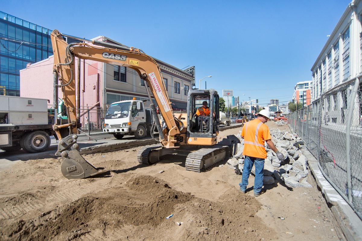 Excavator operator sorting concrete debris during Central Subway utility work on 4th Street.