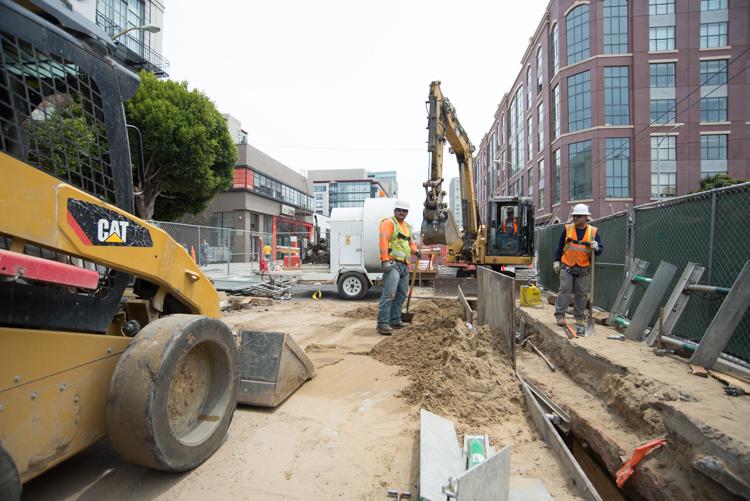 Construction crew operating excavator and compactor on 4th Street sewer line installation project.