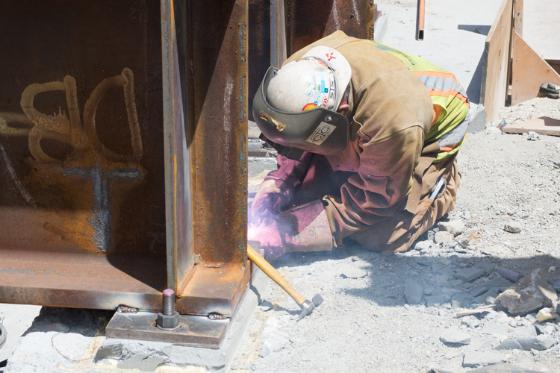 Worker in safety gear welding steel beam at Chinatown Station construction site