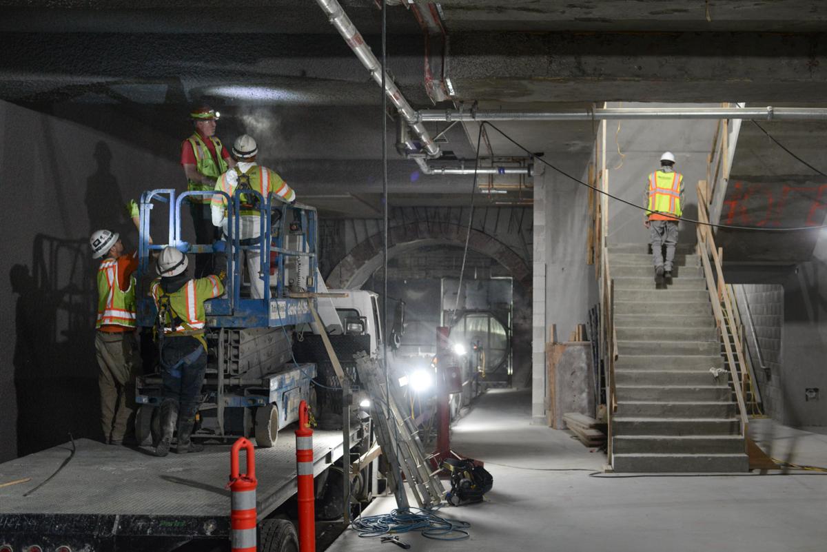 Workers in safety gear construct interior elements of Yerba Buena/Moscone Station underground tunnel.