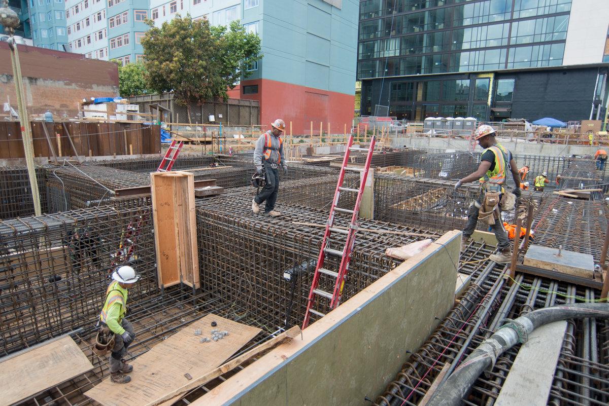 Construction workers install rebar and concrete forms at Yerba Buena/Moscone Station underground excavation site.