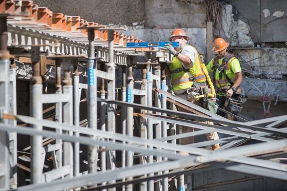 Construction workers in safety gear align structural supports on Union Square Garage renovation project.