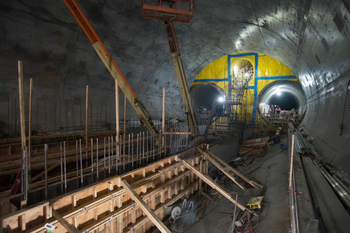 Construction of platform foundation walls in underground transit tunnel with concrete formwork and equipment.