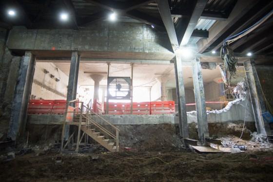 Central Subway construction site showing interior of former Union Square Garage with red barriers and exposed concrete structure under bright lighting.