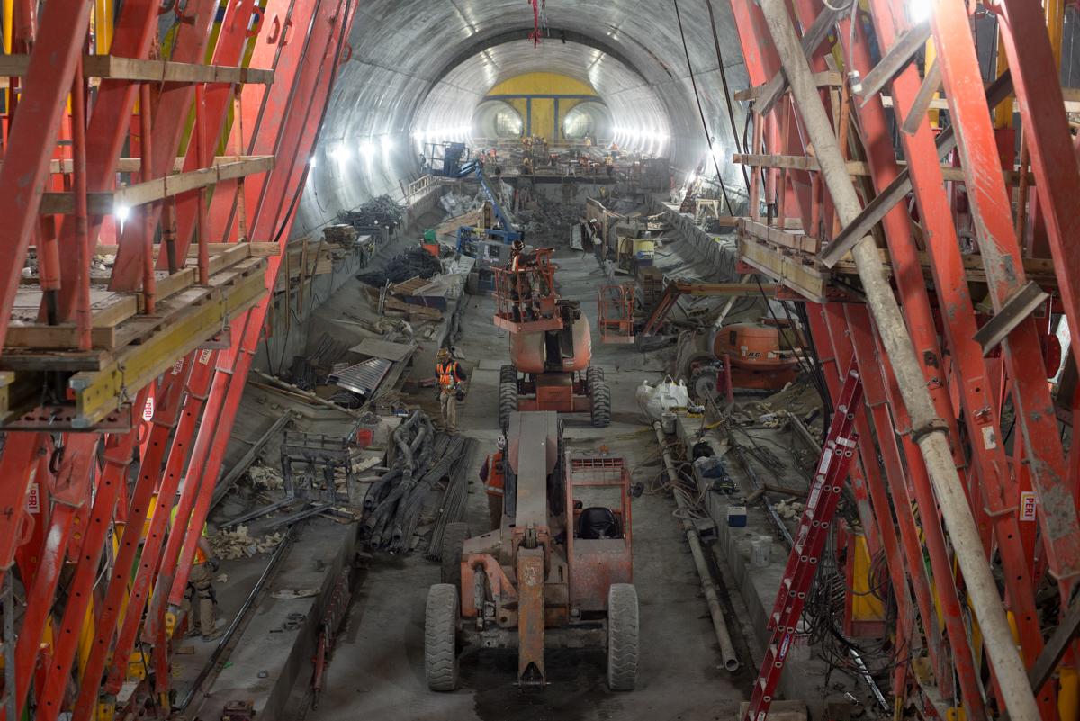 Tunnel interior showing construction equipment and red support structures along excavated passage.