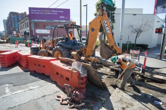 Construction crew operates excavator at 4th Street and Brannan Street for Central Subway project.