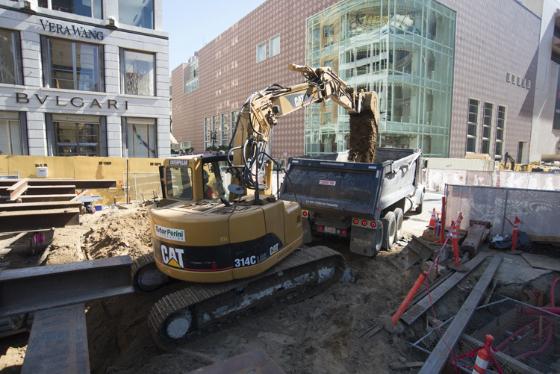 Excavator loading dump truck with excavated material during street construction at Stockton Street and Geary Boulevard.