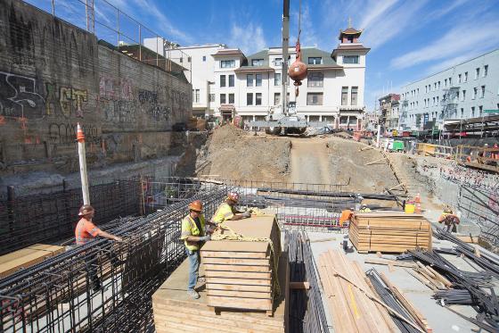 Workers install rebar and wooden forms at construction site for future Chinatown Station on Stockton Street.