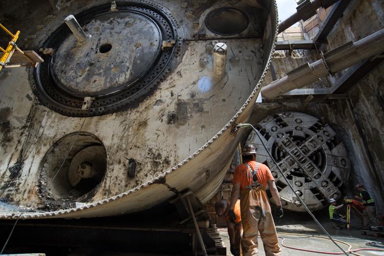 Worker in orange suit disassembling tunnel boring machine at North Beach retrieval shaft.