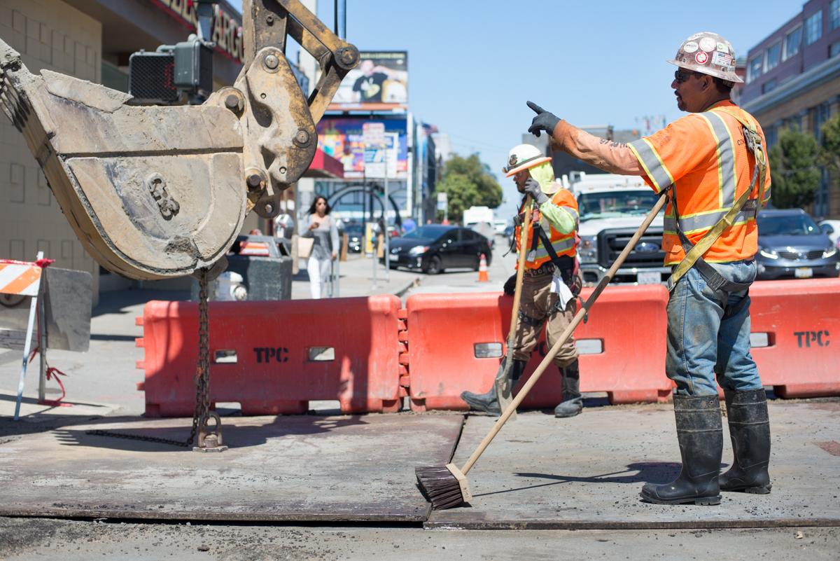 Construction worker operating excavator bucket during sewer slip lining work on 4th Street.