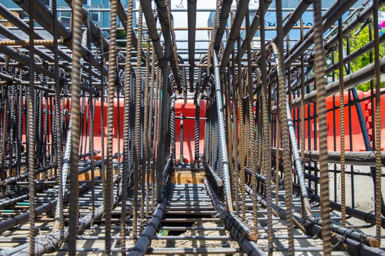 Steel rebar cage framework inside an underground transit station construction shaft with red signage visible in background.