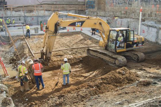 Construction workers and excavators dig out the future Chinatown Station site on Stockton Street.