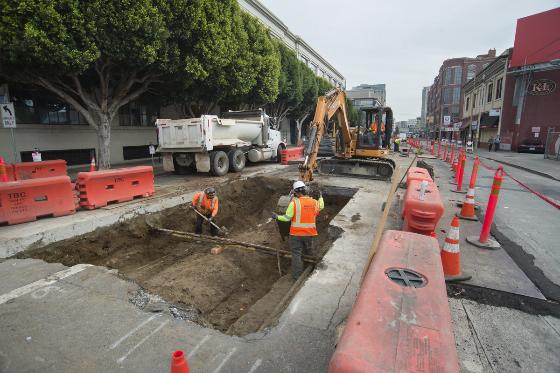 Construction crew excavates roadway on 4th Street to expose main sewer line for Central Subway project.