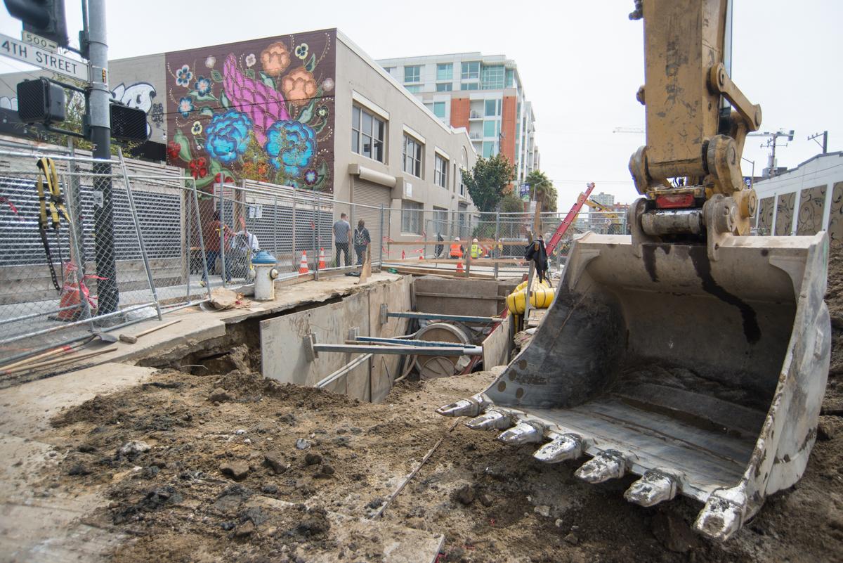 Construction excavation on 4th Street with heavy equipment and utility work in progress.