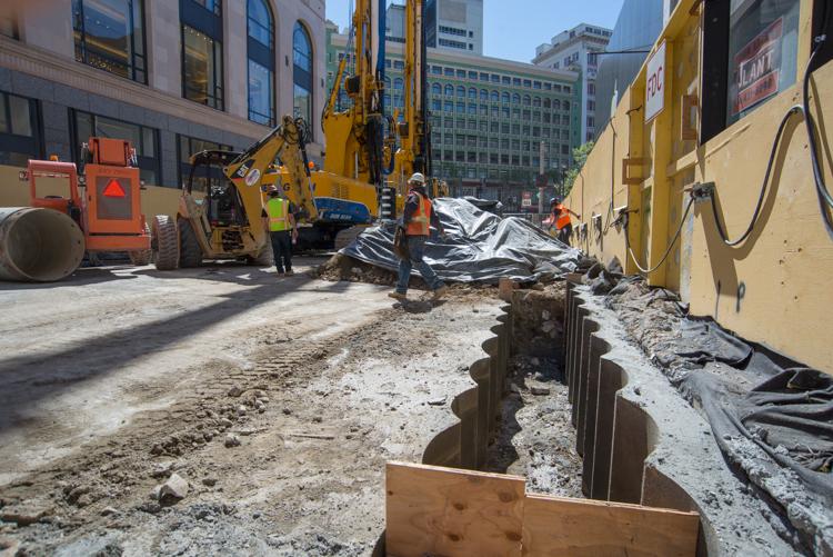 Construction crew with heavy machinery excavating street utilities on Stockton Street in downtown San Francisco.