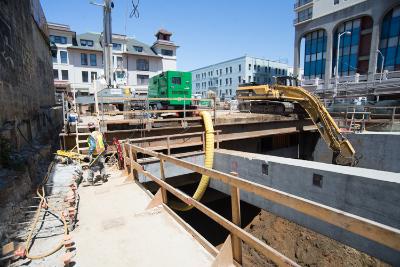 Construction excavation at Chinatown Station headhouse with heavy equipment and wooden support structures.