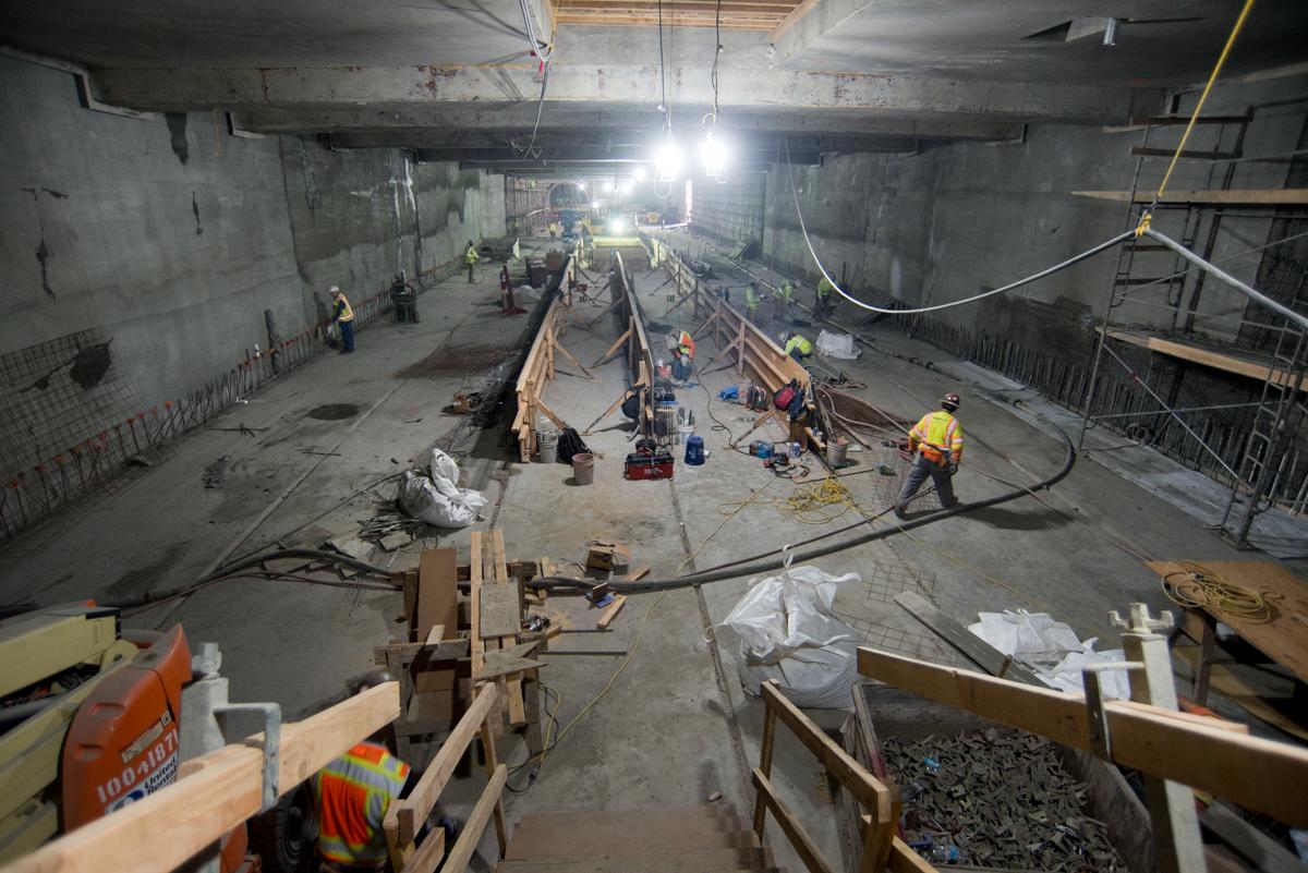 Construction crew assembling rebar and concrete forms inside underground transit station tunnel.