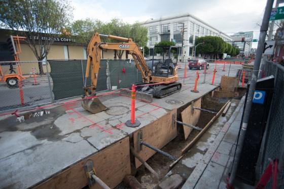 Construction site with excavator and utility trench on urban street near 4th Street Station.