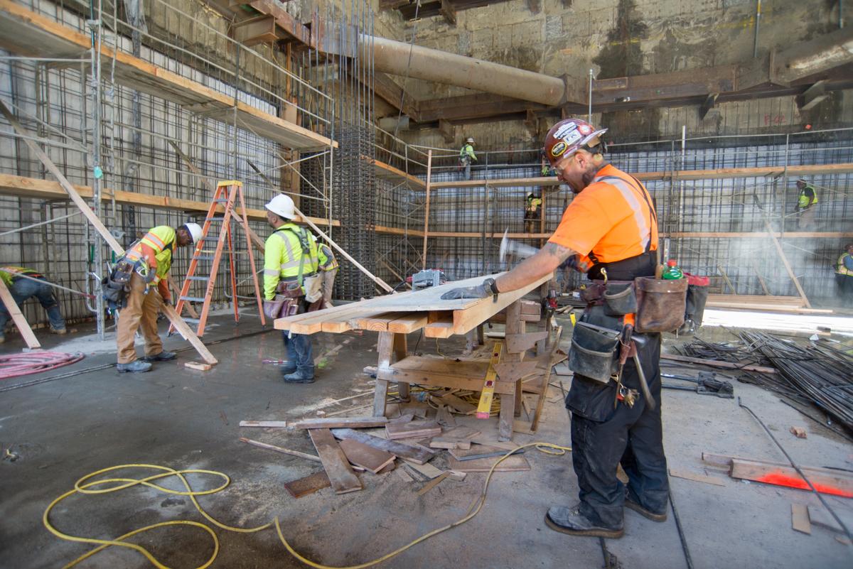Construction workers building concrete forms inside transit station headhouse.