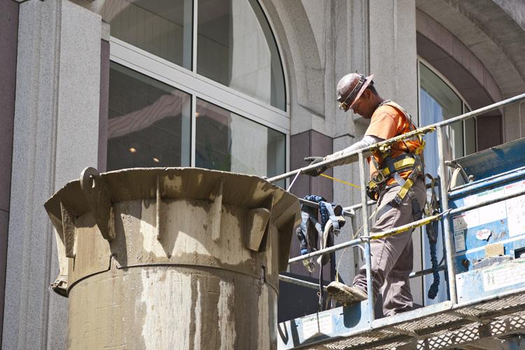 Worker on elevated platform installing underground headwall structure at Union Square construction site.