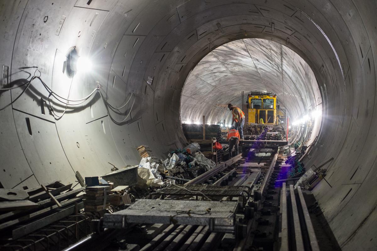 Workers unload concrete forms inside a tunnel under construction for transit track foundations.
