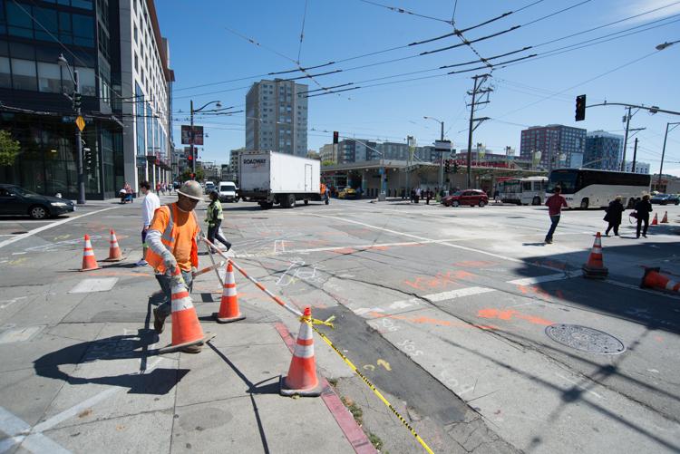 Worker in orange vest removing overhead wires at 4th Street and Townsend intersection in San Francisco.